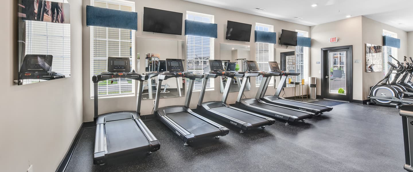 Fitness center featuring treadmills withTVs above