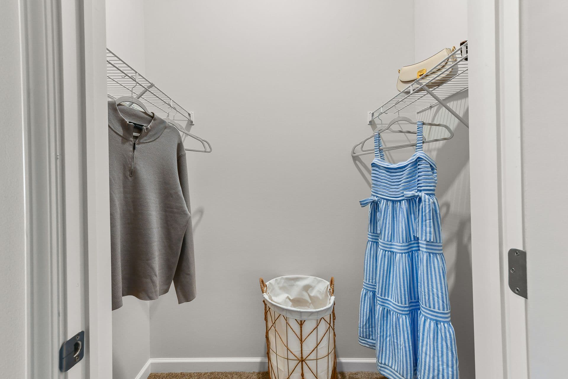 A walk in closet with shirts and dresses hanging on hangers