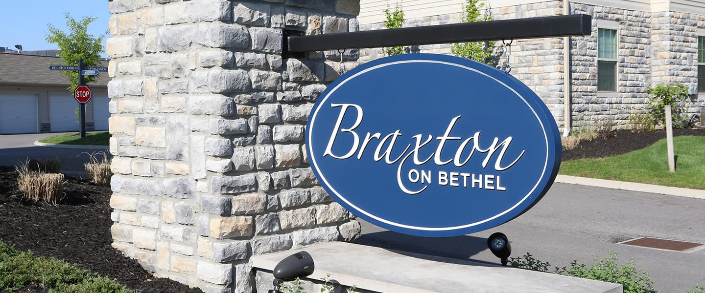 A front-view of an apartment building with inviting landscaping details including trees and bushes.