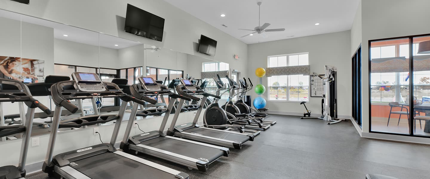 A modern community workout center with exercise equipment and natural light.