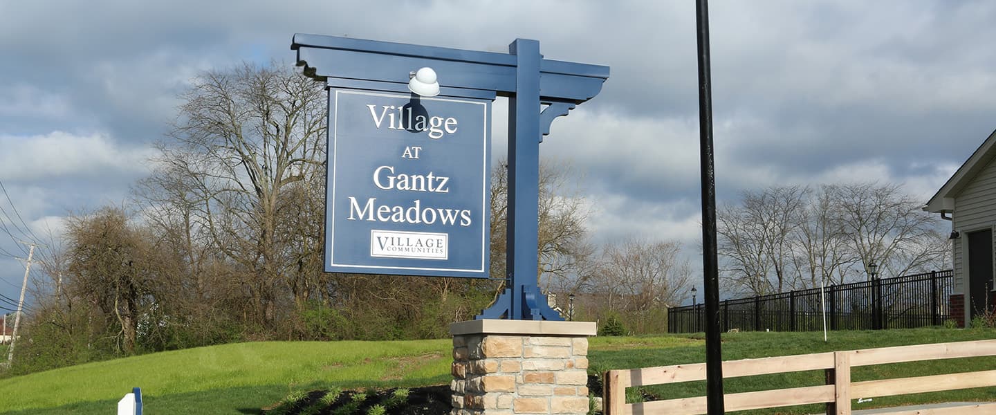 A front-view of an apartment building with inviting landscaping details including trees and bushes.