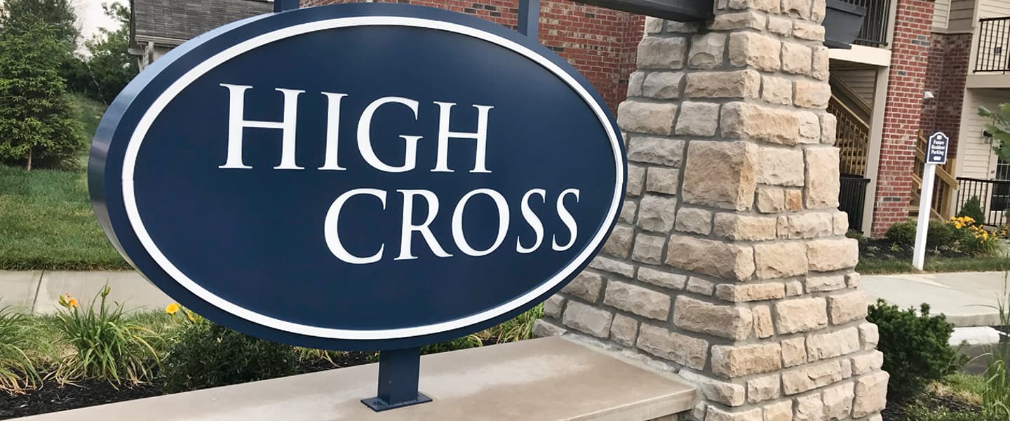 A front-view of an apartment building with inviting landscaping details including trees and bushes.