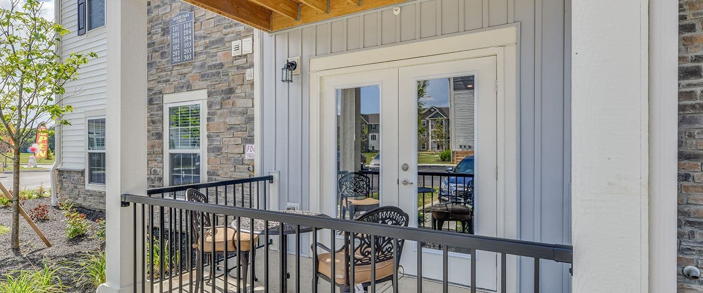 A front-view of an apartment with a private porch complete with patio furnature and landscaping.