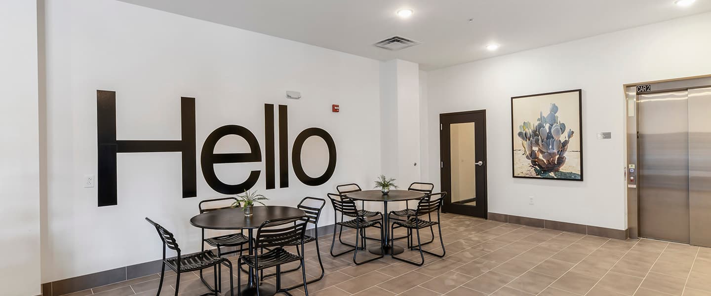 A community space with tables, modern decor and an elevator.