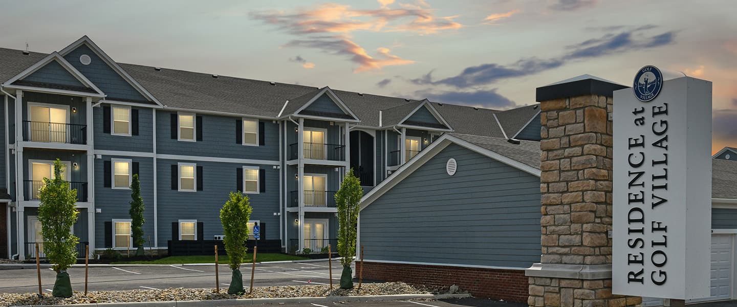 Exterior view of the Residence at Golf Village sign and three story Powell Ohio apartment complex at dusk